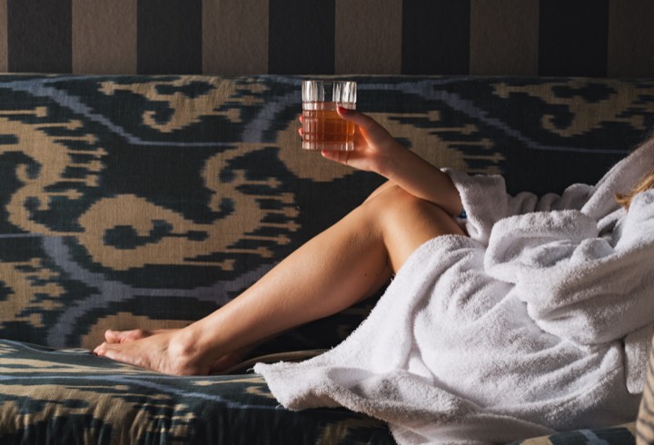 Mannequin en peignoir tenant un Negroni sur un canapé pour Hôtel Infante Sagres à Porto, Portugal.